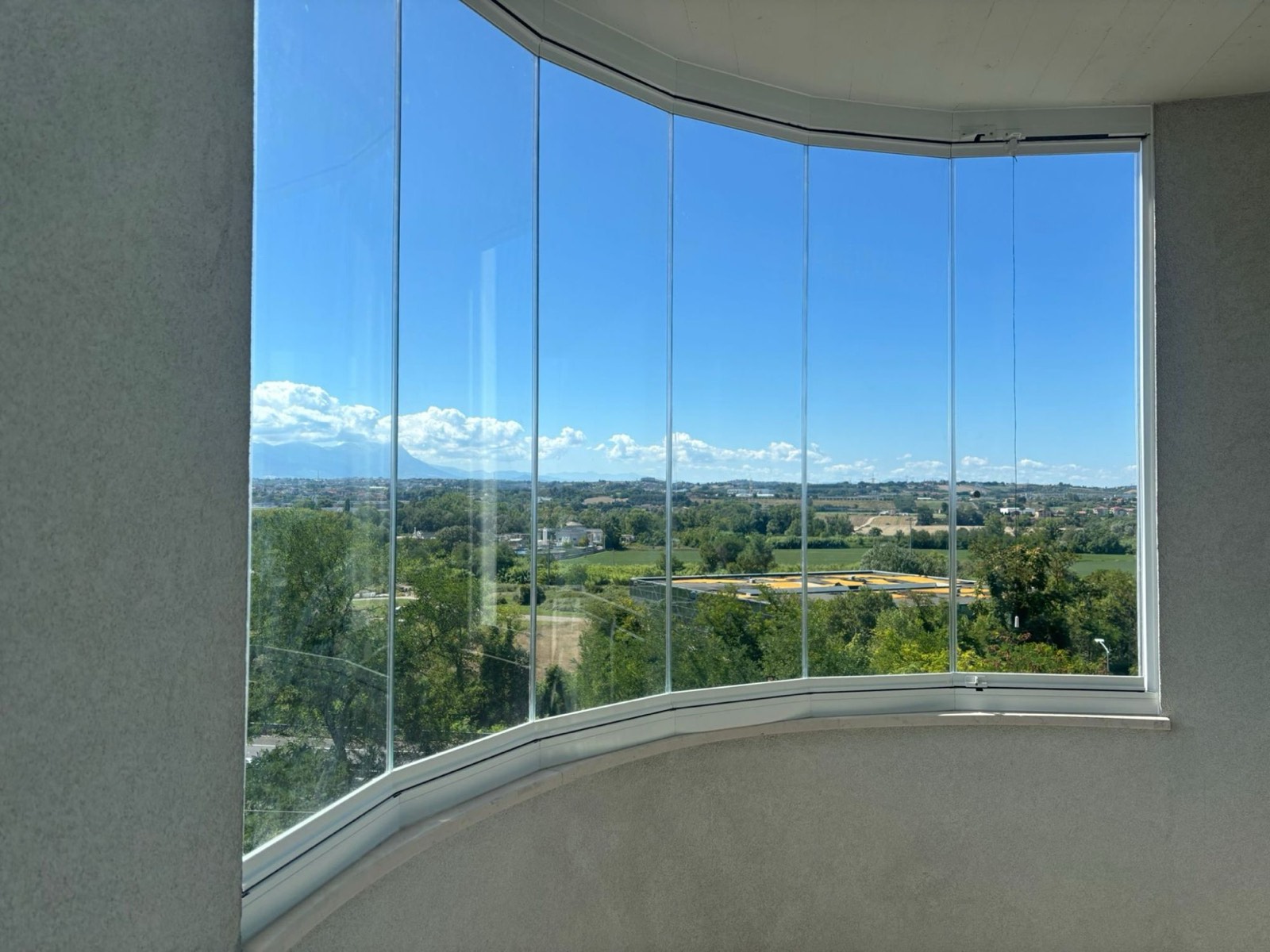 Balcone curvo chiuso con vetrate panoramiche e vista sulla campagna